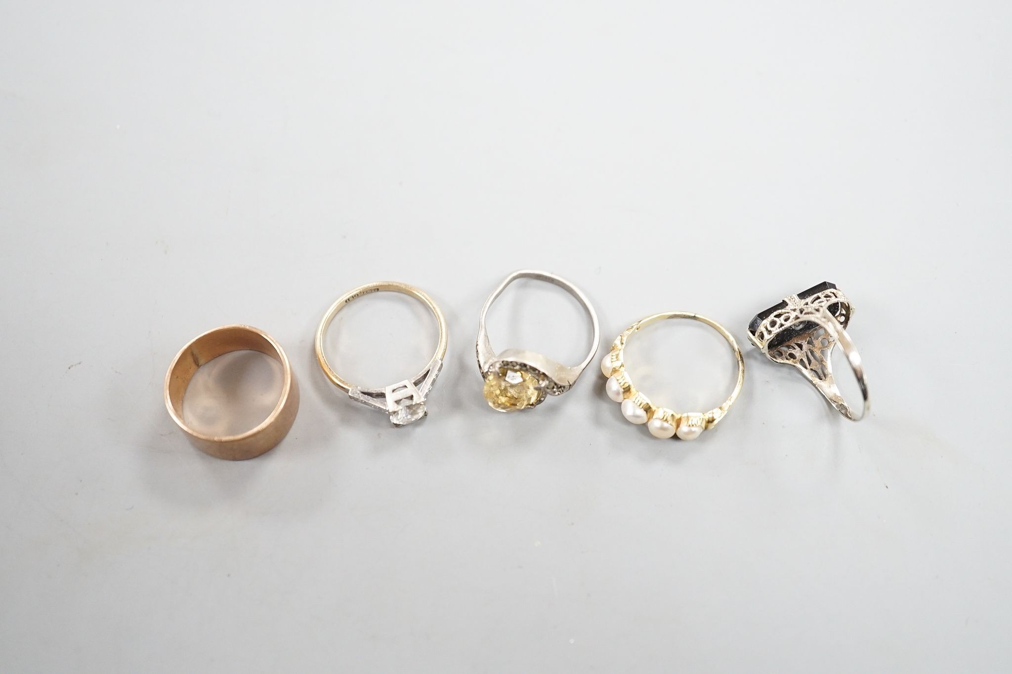 A 9ct gold wedding band, 4.8 grams, a yellow metal and split pearl set half hoop ring, a black onyx and diamond chip set ring, a 9ct and paste ring and one other ring.